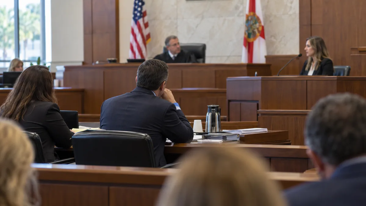 Defense counsel listens during a witness examination in a Florida courtroom